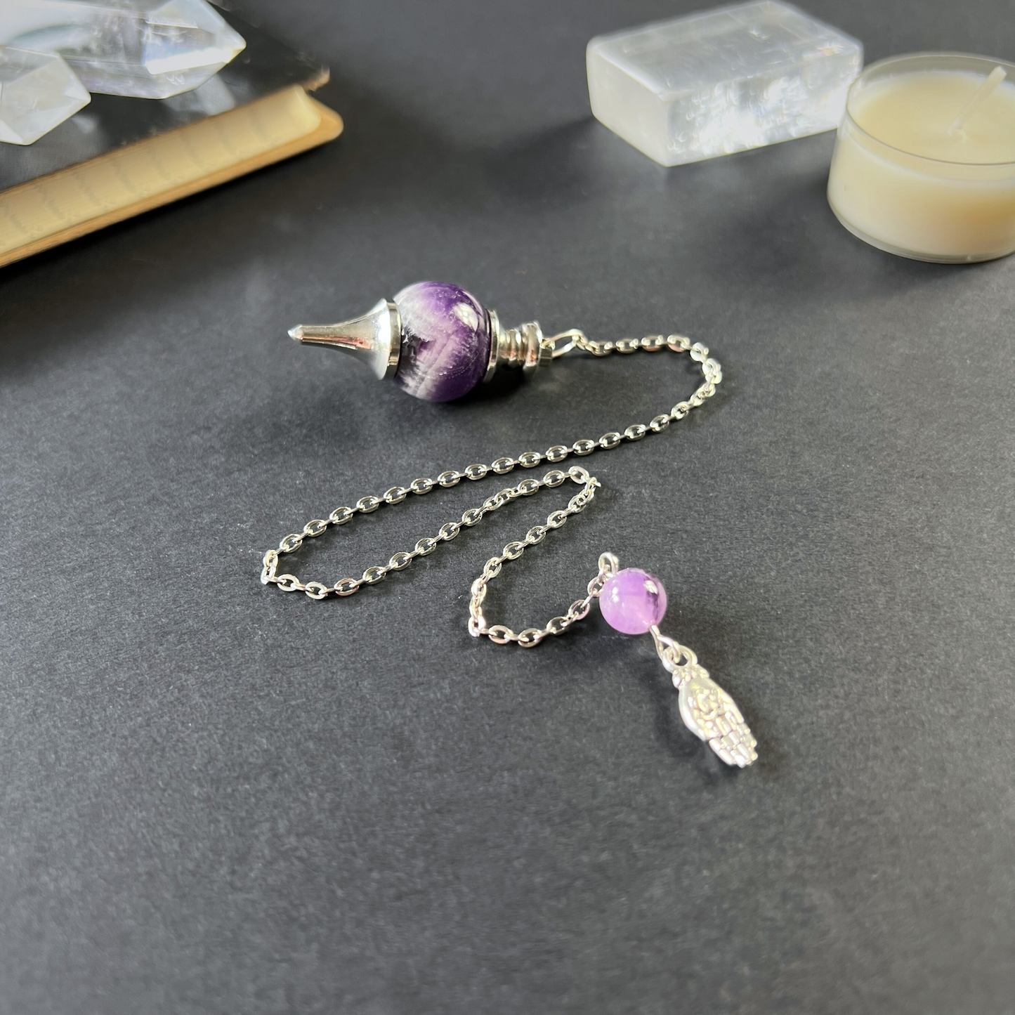 Amethyst and hand holding a lotus Sephoroton dowsing pendulum