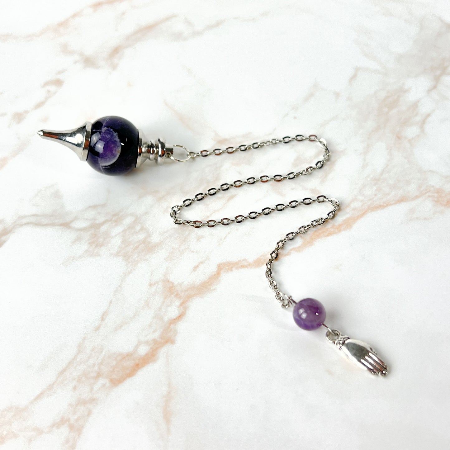 Amethyst and hand holding a lotus Sephoroton dowsing pendulum Baguette Magick