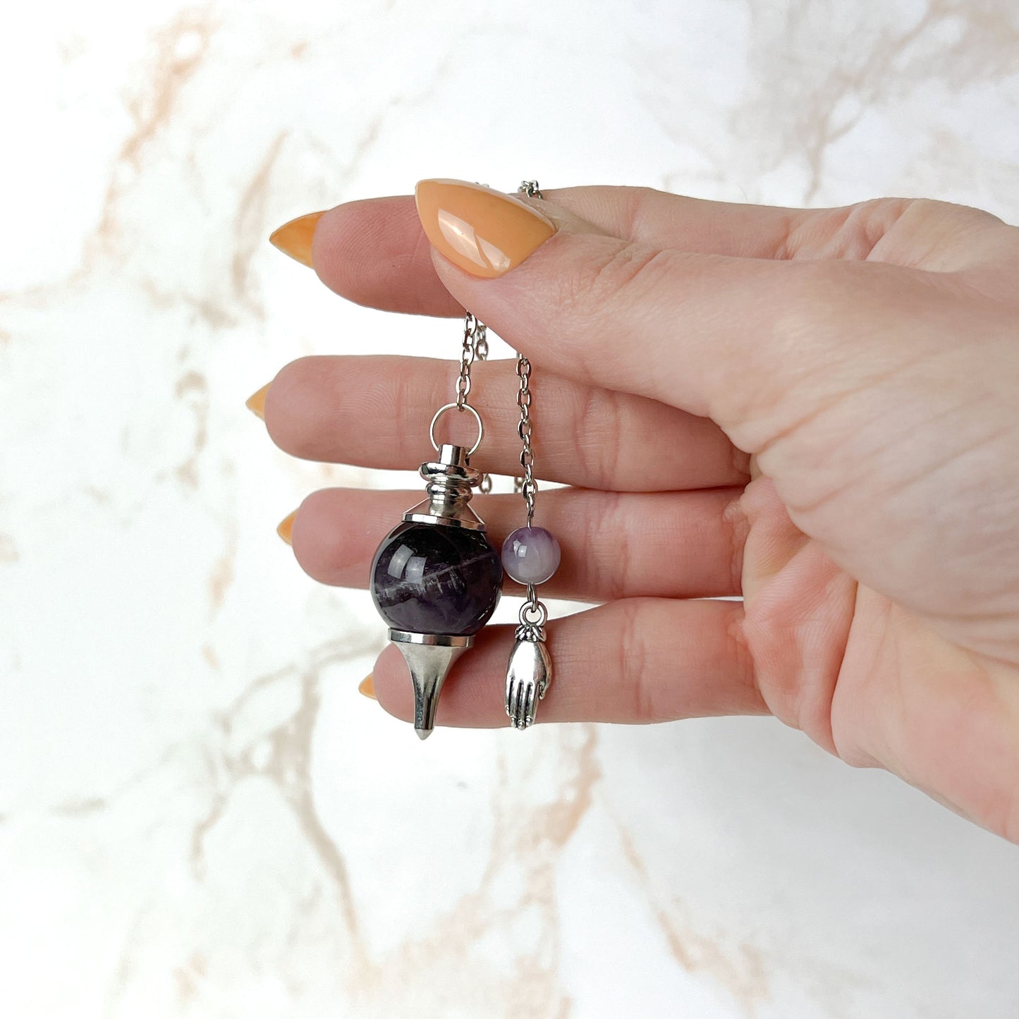 Amethyst and hand holding a lotus Sephoroton dowsing pendulum Baguette Magick