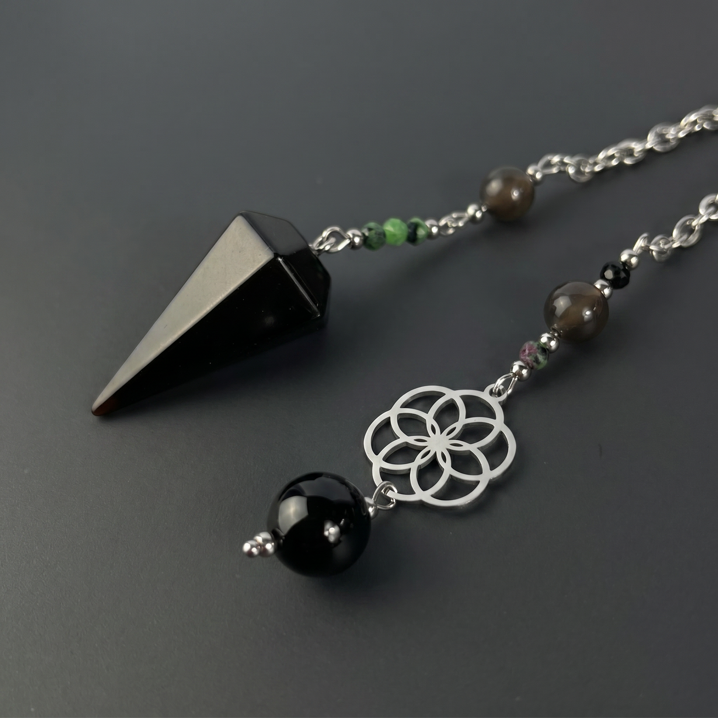 Pendule de radiesthésie en obsidienne, rubis zoïsite et onyx, avec breloque fleur de vie